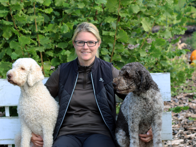 Anja Kolbe-Nelde sitzt auf einer Bank und jeweils rechts und links von ihr sitzt ein Hund.