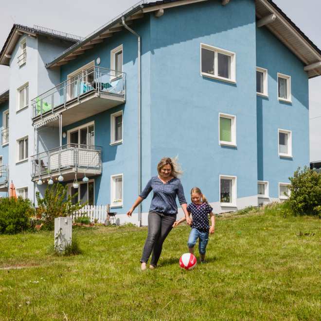 Eine Familie spielt Fußball vor dem Eigenheim
