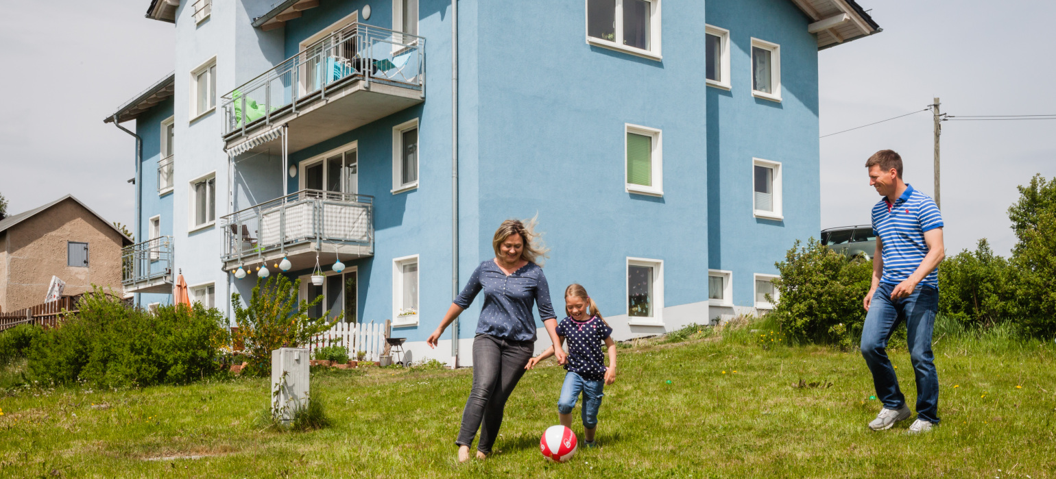 Eine Familie spielt Fußball vor dem Eigenheim